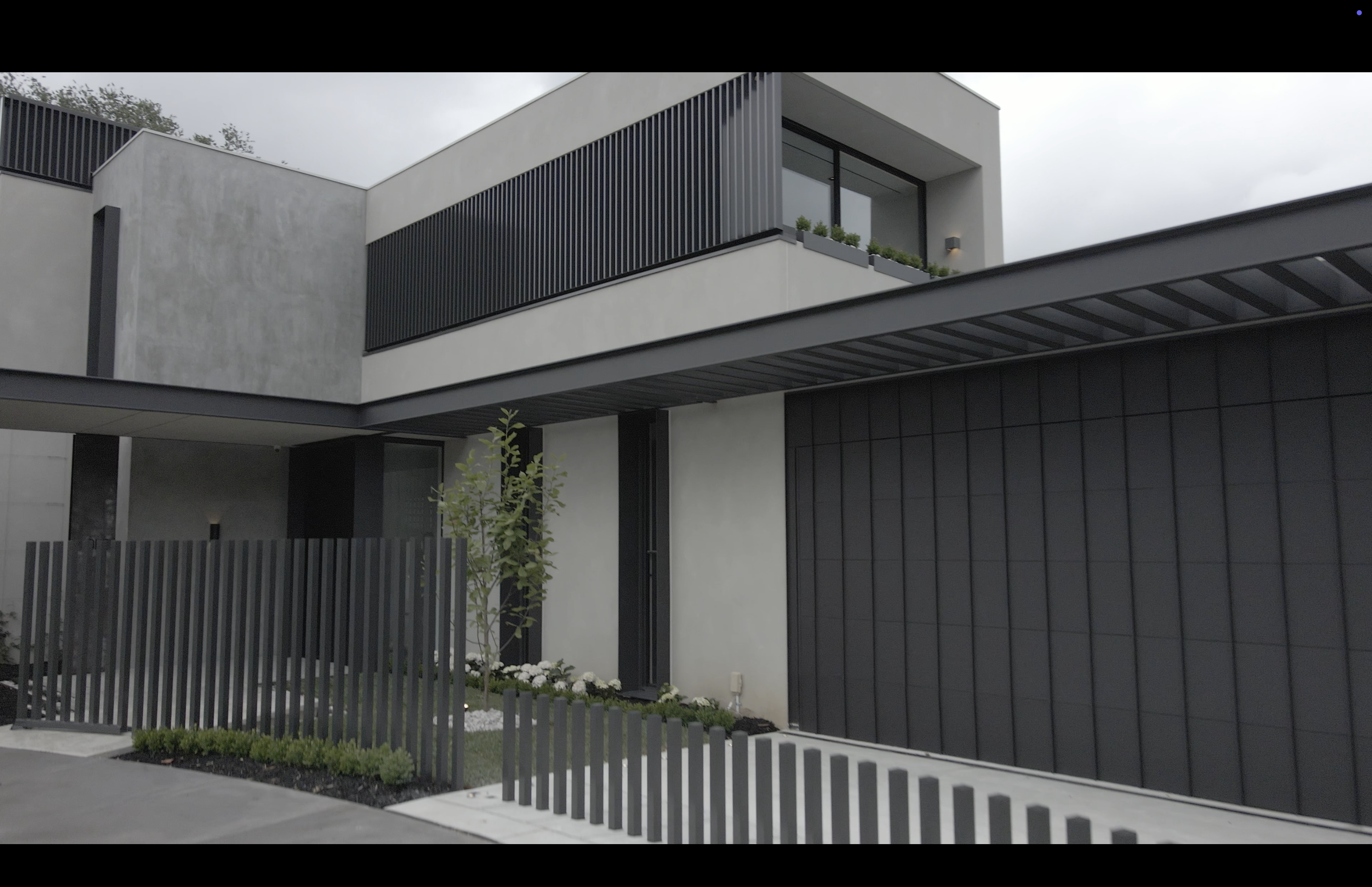 Modern two-storey home exterior with dark fencing and landscaping
